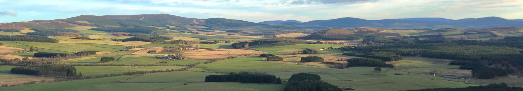 A sun-dappled landscape of fields, farms and forests looking towards Deeside in Aberdeenshire, Scotland. Credit: Kirsty Blackstock